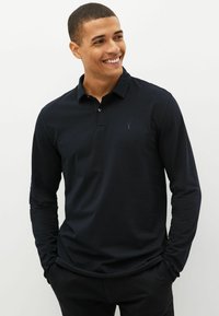 Marineblaue Langarm-Polohemd aus Baumwollmischung; mit einer Knopfleiste und einem kleinen gestickten Logo auf der Brust.
