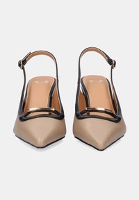 Tacones tipo slingback en beige y negro con punteras puntiagudas, fabricados en cuero, acentos de hardware dorado y un diseño minimalista. Textura suave.
