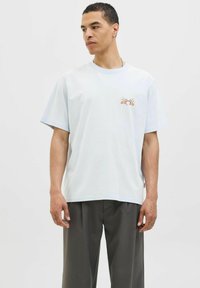 Lichtblauw katoenen T-shirt met korte mouwen, ronde hals en een klein geborduurd kersenontwerp op de linkerborst. Gladde textuur, ontspannen pasvorm.