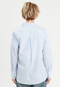 Gestreept shirt in lichtblauw en wit, met een puntkraag, lange mouwen en een rugplooitje voor extra bewegingsvrijheid. Van katoen.