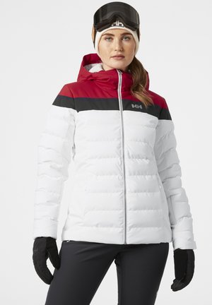 White puffer jacket with red and black color block at shoulders, featuring a front zipper, hood, and ribbed cuffs. Model wearing ski gloves.
