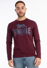 Burgundy long-sleeve t-shirt with a blue lion graphic and "LONSDALE LONDON" text printed on the front; soft cotton fabric; crew neckline.