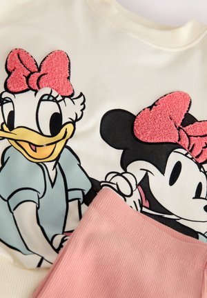 Kremfarvet sweatshirt med broderede figurer med lyserøde sløjfer, kombineret med lyserødt ribstof i bunden. Lyse farver og legende design.