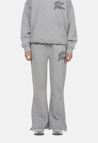 Grau Baumwoll-Sweatshirt und Hose im Set, ausgestattet mit lockerer Passform, gerippten Bündchen und bedrucktem Text. Die Hose hat ein ausgestelltes Design und einen elastischen Bund.