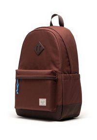 Smešasti ruksak u smeđoj boji s okruglim oblikom, prednji džep s patentnim zatvaračem i plavom ručkom te dijamantni akcent na glavnom telu.