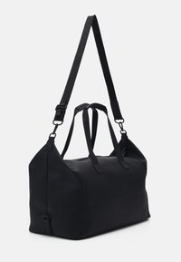 Sac de sport noir en matériau lisse, avec une fermeture éclair sur le dessus, des poignées de transport doubles et une bandoulière réglable.