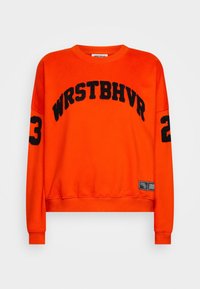 Sudadera naranja con texto negro "WRSTBHVR" en el pecho y "23" en una manga. Presenta un cuello redondo y puños acanalados.