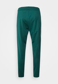 Zelené sportovní kalhoty s pohodlným elastickým pasem, zúženými nohavicemi a hladkou texturou. Na zadní straně jsou minimální detaily.