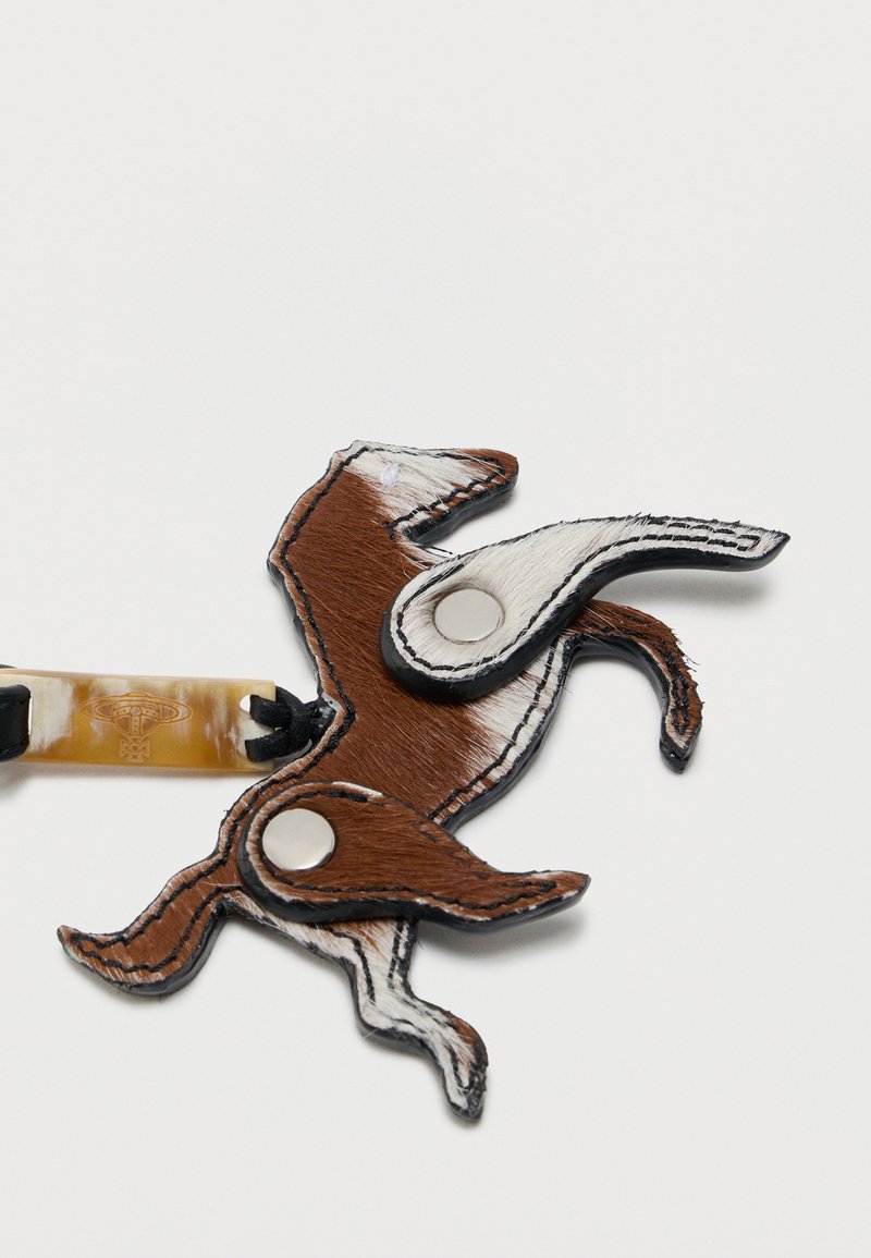 Portachiavi decorativo a forma di cavallo in pelle marrone e bianca con rivetti in metallo e un attacco a strappo beige.