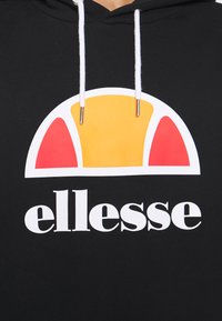 Sudadera negra con un gran logotipo colorido con acentos en amarillo, rojo y blanco. Incluye cordones blancos con extremos de metal.