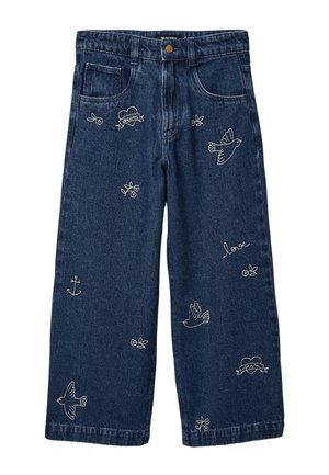 Jean large bleu foncé avec des broderies blanches d'oiseaux, de fleurs, d'ancres et de cœurs, avec les mots « rêve » et « amour ».