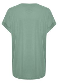 Světle zelené tričko s krátkým rukávem, volného střihu, kulatým výstřihem a hladkou, jemnou texturou. Má decentní šev na zadní straně.