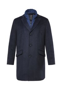 Granatowy wełniany płaszcz o teksturowanym wykończeniu, z dużymi klapami, trzema przednimi guzikami i dwoma kieszeniami po bokach. Wewnętrzny kołnierz podszyty niebieskim nylonem.