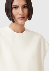 Kermavärvi oversized-nuttu, jossa on pyöreä pääntie, pehmeä tekstuuri ja raglan-hihat, joissa on hillittyjä ompeluohjuksia.