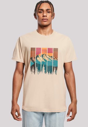 Beige Baumwoll-T-Shirt mit einem grafischen Motiv von Bergen und Bäumen in Türkis, Orange und Braun, vor einem gestreiften Sonnenuntergangshintergrund.