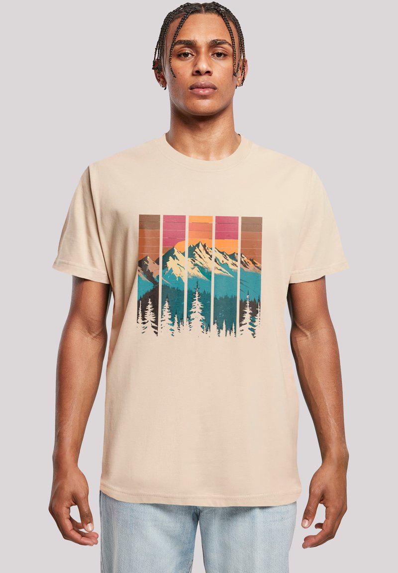 Beige katoenen t-shirt met een grafisch ontwerp van bergen en bomen in teal, oranje en bruin, met een gestreepte zonsondergangsachtergrond.