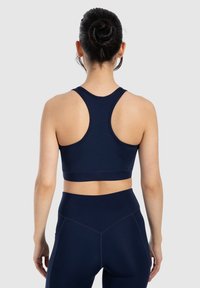 Sujetador deportivo azul marino hecho de material elástico con un diseño de espalda en forma de T. Cuenta con costuras planas y una banda ancha para mayor soporte. Combina con leggings a juego.