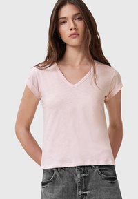 T-shirt a maniche corte V-neck rosa chiaro con maniche arrotolate. Tessuto morbido e leggero; vestibilità comoda; abbinato a pantaloni grigio scuro.