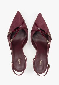Bordowe zamszowe szpilki z wąskim noskiem, z krzyżującymi się paskami, lśniącymi akcentami oraz złotymi elementami. Gładkie wnętrze z logo.
