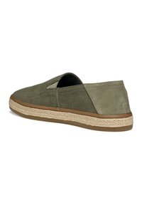 Zapatillas de lona verde oliva tipo slip-on con una suela intermedia envuelta en yute y una suela de goma. Presentan paneles laterales elásticos para facilitar su uso.