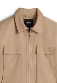 Beige canvas jacket featuring a zip front, collared neck, and two chest pockets. Stitched detailing and a durable texture are prominent.