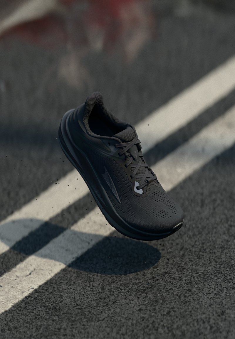 Scarpa da corsa nera con parte superiore in rete, texture perforata e suola ammortizzata. Presenta lacci e un profilo aerodinamico.