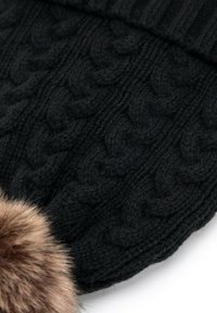 Cappellino a maglia nero con motivo a treccia e un pompon in pelliccia sintetica marrone morbida. La texture appare morbida e spessa.