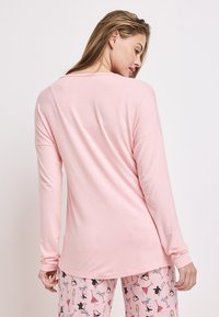 Långärmad, ljusrosa topp med avslappnad passform och rundad halsringning. Har mjukt tyg och något sänkta axlar. Sammanpassad med mönstrade rosa pyjamabyxor.