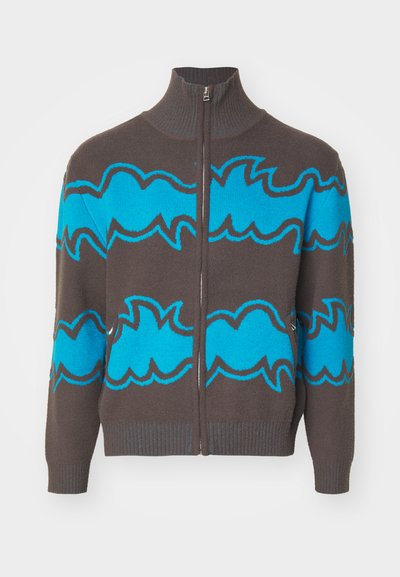 Pull zippé en tricot marron foncé arborant de larges motifs en vagues turquoise, un col haut et des bords côtelés aux poignets et au bas. Texture douce, coupe décontractée.