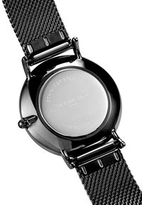 Czarny stalowy zegarek z siatkowym paskiem. Tył jest gładki z wygrawerowanym tekstem, wskazującym na markę i szczegóły mechanizmu.