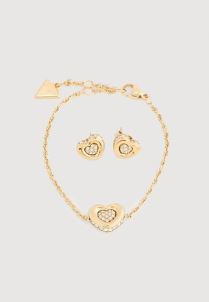 Goldfarbene Schmucksets bestehend aus einem herzförmigen Armband und Ohrringen, verziert mit klaren Strasssteinen und einem gedrehten Kettendesign.