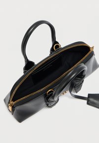 Μαύρη δερμάτινη τσάντα χειρός με χρυστό φερμουάρ και λαβές. Το εσωτερικό διαθέτει υφασμάτινη επένδυση και θήκη για κάρτες, με δομημένο ορθογώνιο σχήμα.