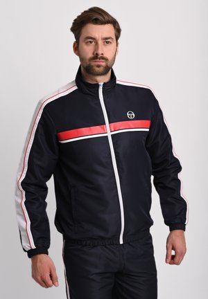 Navy zip-up tracksuit jacket with red and white horizontal stripes, elastic cuffs, and a logo on the left chest. Smooth, glossy fabric.