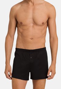 Boxers de algodón negros con una cinturilla elástica, cierre frontal de botón y bolsillos laterales. Diseño sencillo, textura suave y ajuste a medida.