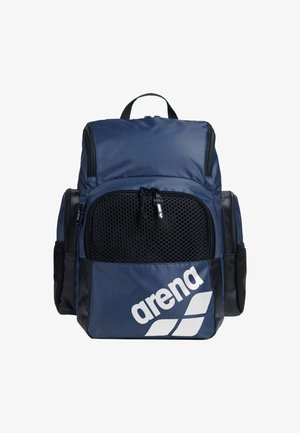 Námořnická modrá batoh s černými akcenty, síťovou přední kapsou a bílým logem. Obsahuje více kapes a je vyroben z odolného, texturovaného materiálu.