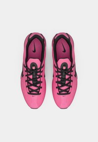 Roosa paar Nike jooksutossusid mustade paelte ja mustade Nike logo'dega, vaadatuna ülevalt valgel taustal.