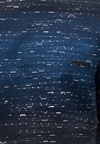 Knit shirt in shades of navy blue with a textured pattern of zigzag lines and horizontal stripes. Features branded logo in subtle embroidery.