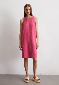 Rosa Leinen-Ärmelloses Kleid mit lockerer Passform, Rundhalsausschnitt und geradem Saum. Das Model trägt beige Rutschsandalen.