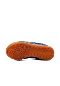 Suela de zapato con un goma naranja texturizada que presenta patrones circulares y de crestas; la parte superior de tela azul es visible en el borde.