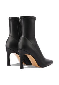 Stivaletti in pelle nera con punta affusolata, silhouette allungata e sottile tacco a stiletto. Presentano una zip sul retro e dettagli di cucitura.