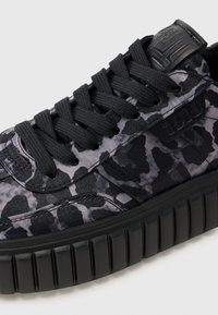 Des baskets noires et grises avec un upper texturé, une semelle en caoutchouc épaisse, des lacets plats et un soutien de la cheville rembourré.