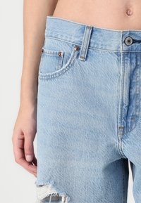 Lichtblauwe denim jeans met een rafelige zoom en versleten accenten. Voorzien van koperen klinknagels en stikseldetails. Hoge taille met voorzakken.