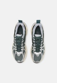 Nike-sneakers med en grön nätövre, silverdetaljer, tjocka krämfärgade sulor och en svart logo på tungan.