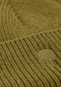 Olijfgroene gebreide stof met verticale ribbeltextuur en een cirkelvormig geweven detail. Het garen lijkt dik en zacht, wat warmte suggereert.