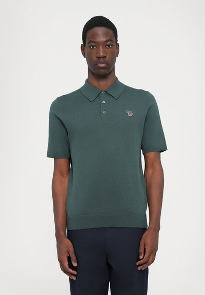 Polo de punto de manga corta en verde oscuro. Presenta un cuello con solapa, una tapeta de tres botones y un pequeño logo de animal bordado en el pecho.