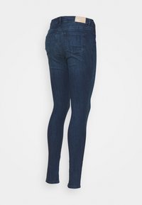 Mörkblå skinny jeans med midja, slät textur och bakficka utan synliga detaljer eller utsmyckningar.