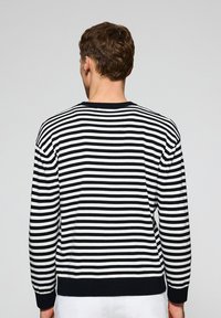 Black and white striped sweater with a crew neck, ribbed cuffs and hem, made from a soft knit material, featuring a relaxed fit.