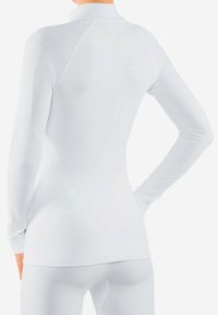 Haut à manches longues blanc avec un col montant, texture côtelée et design ajusté. Présente des accents d'épaules sans couture et une silhouette élégante.