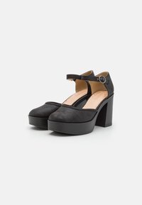 Černé lodičky na vysokém podpatku s kulatou špičkou a páskem. Vyrobené z texturovaného materiálu. Mají robustní blokový podpatek a dekorativní přezku na pásku.