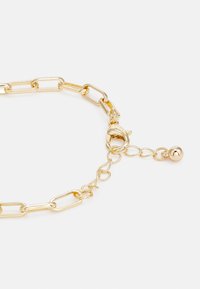 Pulseira de cadeia de ouro com elos alongados, fecho de lagosta e uma corrente ajustável com um pequeno charme esférico na extremidade.